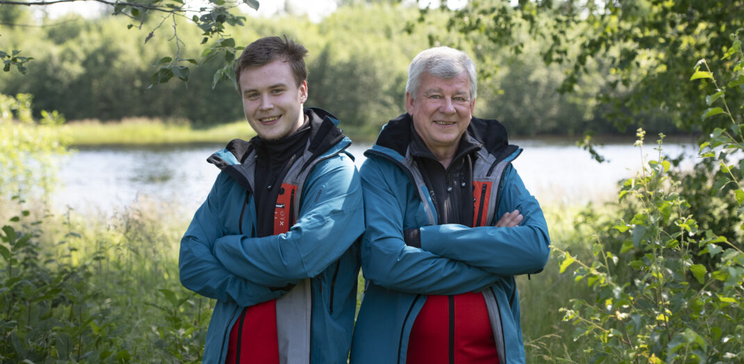 Två män i vandringskläder står vid sjön Fryken- 