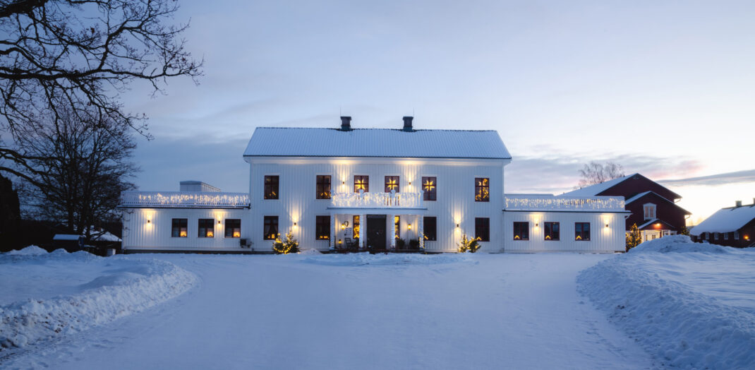Ulvsby herrgård iskall vintermorgon i soluppgång. Snö på taket och marken. Julbelysning i fönster och ute.