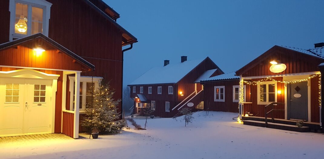 Ulvsby herrgård jultider. Röda Flygelbyggnader med snö och julbelysning.
