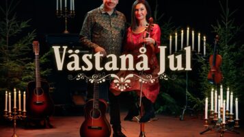 Västanå Jul. En man och en kvinna i röd klänning. Ljusstakar och en fiol.
