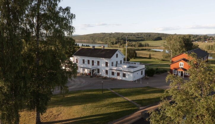 Vit herrgård och röd flygelbyggnad vid sjön Fryken